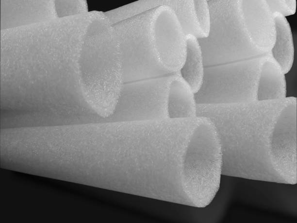 side view of a pile of white foam tubes in the shape of a hollow pipe. a tubular, perforated foam sponge used for packing fluorescent light bulbs, electronic or sensitive items